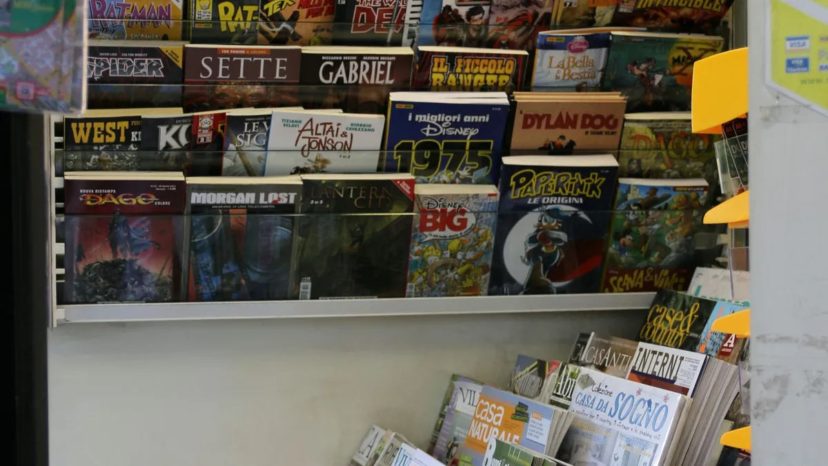 Edicola urbana con quotidiani e riviste esposti accanto a lettori in transito